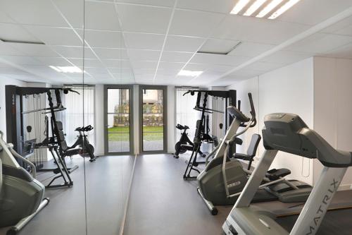 un gimnasio con varias máquinas de correr en una habitación con ventanas en Résidence Néméa Clermont Centre, en Clermont-Ferrand