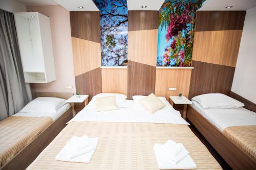 two twin beds in a room with two windows at Hotel Herceg in Međugorje