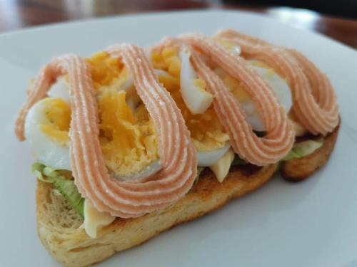 un sándwich con huevos y tocino en un plato blanco en Alona Vikings Lodge 1, en Panglao