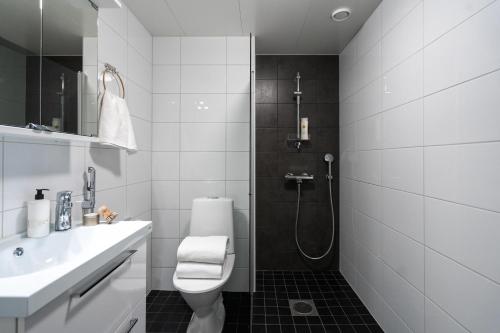 a bathroom with a toilet and a sink and a shower at Roost Rantatie 18 in Tampere