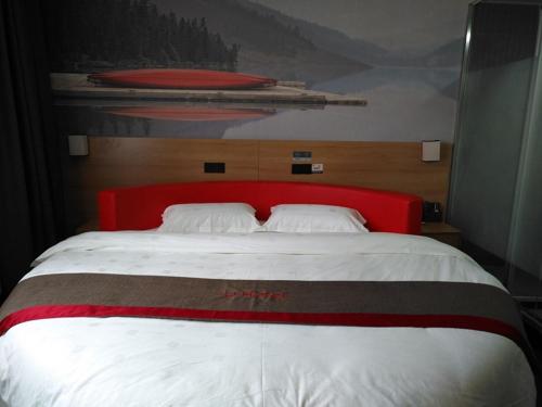 een groot bed met een rood hoofdeinde in een slaapkamer bij Thank Inn Chain Hotel Jiangsu Taizhou West Passenger Station Jianhang Store in Taizhou