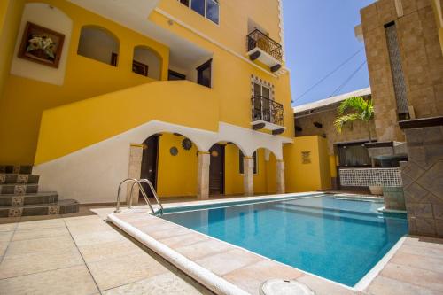 a villa with a swimming pool in front of a building at Suites Flamboyanes in Mérida