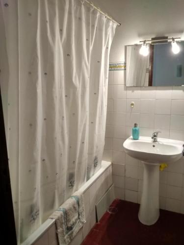 a bathroom with a shower curtain and a sink at Apartamento Almargem in Conceição