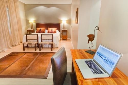 a bedroom with a bed and a laptop on a desk at Villa Isidro Hotel Boutique & Spa in San Isidro