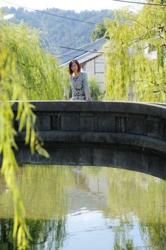 a woman standing on a bridge over a body of water at Kinosaki Yamamotoya in Toyooka