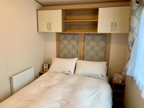 a small bedroom with a bed with white sheets at Shorefield country Park, in Milford on Sea