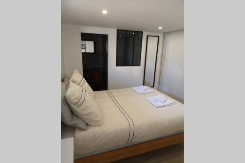 uma cama com lençóis brancos e almofadas num quarto em Le Bigorneau em Langueux