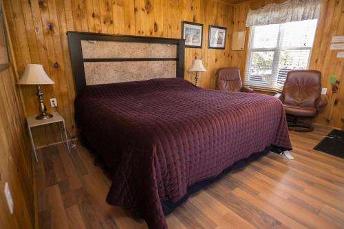 a bedroom with a bed and two chairs and two windows at North Rustico Motel & Cottages in North Rustico