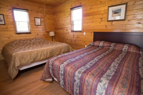 a bedroom with two beds in a log cabin at North Rustico Motel & Cottages in North Rustico