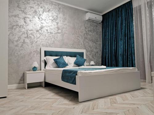 a bedroom with a large white bed with blue pillows at Villa George in Constanţa