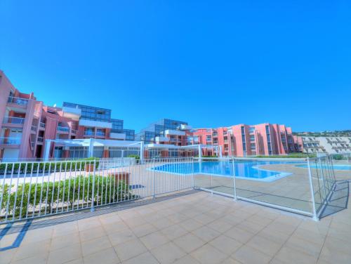 un court de tennis avec un filet de tennis et quelques bâtiments dans l'établissement STUDIO 4 PERS, PKG, 1ERE LIGNE MER, PISCINE, TENNIS, à Sète