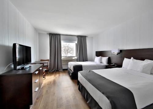 ein Hotelzimmer mit 2 Betten und einem Flachbild-TV in der Unterkunft Hotel Newstar Montréal in Montreal