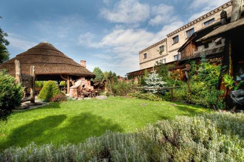 a garden with a thatched building and a grass yard at Hotel Zameczek in Książ Wielki