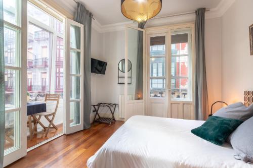 a bedroom with a bed with white sheets and windows at 2MAYO by Kyosai in Bilbao