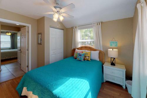 um quarto com uma cama azul e uma ventoinha de tecto em 103 - Sea Cottage em St. Pete Beach