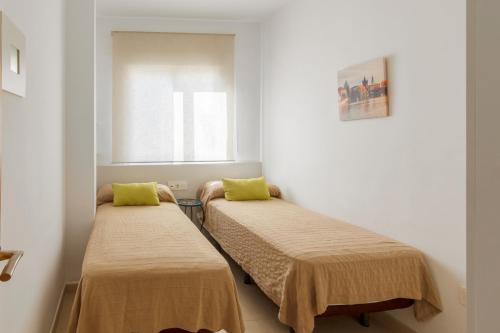 two beds in a small room with a window at Apartamentos Montedunas in Barbate