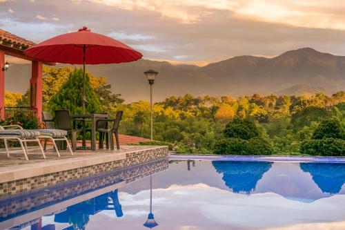 a house with a swimming pool with a red umbrella at Hotel Campestre Solar De La Luna in Armenia