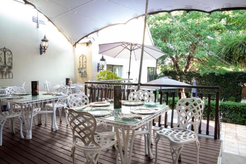 a patio with white tables and chairs and an umbrella at InnJoy Boutique Hotel in Centurion