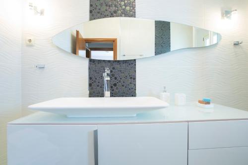 a white bathroom with a sink and a mirror at Villa Ventalia in Nikiana