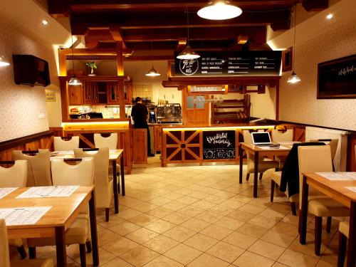 a restaurant with wooden tables and chairs and a kitchen at Nádasdi Ház in Szekszárd