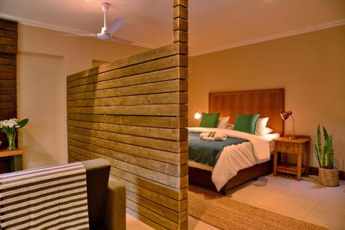 a bedroom with a bed and a wooden wall at La Perle in Ballito