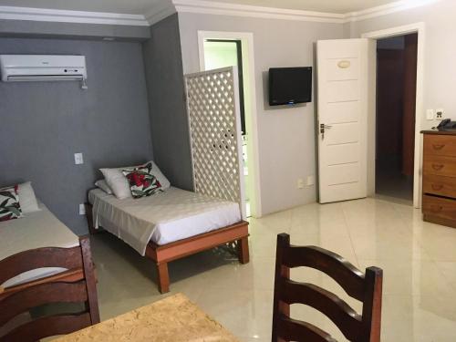 1 dormitorio con 1 cama, 1 silla y TV en Pousada Marbella, en Búzios