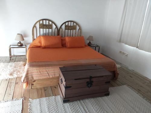 a bedroom with a bed with an orange bedspread and a wooden trunk at La Casita in Garzón