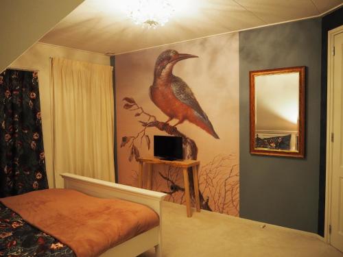 a bedroom with a painting of a bird on the wall at Bed & Brochje Burgum in Burgum