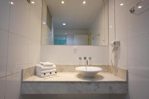 a bathroom with a sink and a mirror and towels at Hotel Dunamys Curitiba in Curitiba