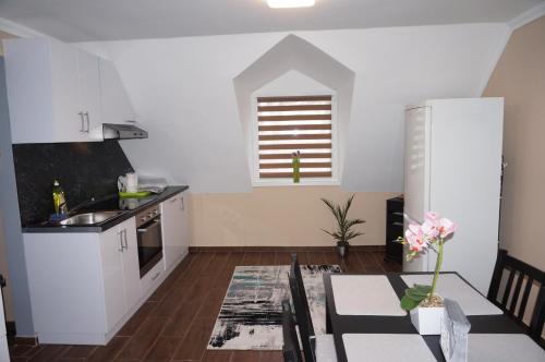 a kitchen with white cabinets and a table with a dining room at Toscana 4 Debrecen in Debrecen