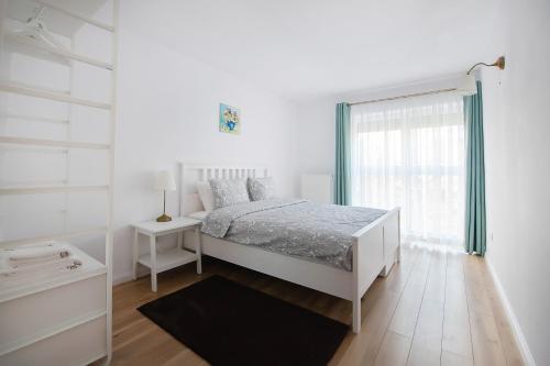 a white bedroom with a bed and a window at Barko Residence 1 in Braşov