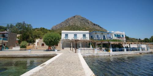 a building next to a body of water with a mountain at Afrodite Luxury Rooms in Telendos