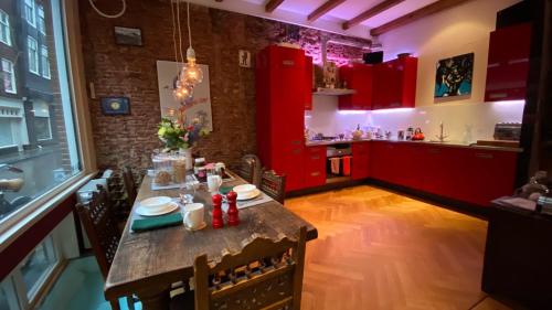 eine Küche mit roten Schränken und einem Tisch mit Stühlen in der Unterkunft The Lastage Inn - Bed & Breakfast in Amsterdam