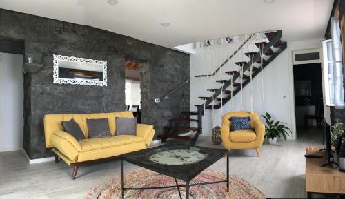 a living room with a yellow couch and a chair at GRANARY'S HOUSE in Sete Cidades