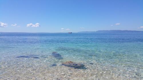 a beach with clear water and a boat in the distance at Volcano Rijeka in Rijeka