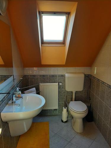 a bathroom with a sink and a toilet and a window at Kondics Apartmanház in Sárvár