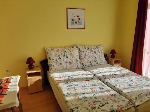 a bedroom with a bed with a flowery bedspread at Kondics Apartmanház in Sárvár