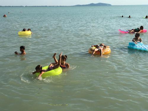 a group of people in the water at the beach at Balaton Wellness Tom Cat nyaraló 1 wellness és 1 gyermekbarát apartmannal in Kővágóörs