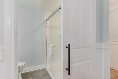 a white bathroom with a glass shower door at John Yancey Oceanfront Inn in Kill Devil Hills
