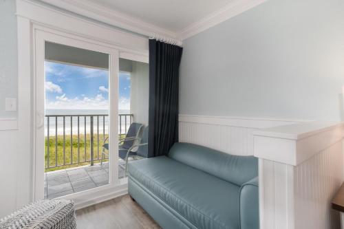 a living room with a couch and a balcony at John Yancey Oceanfront Inn in Kill Devil Hills