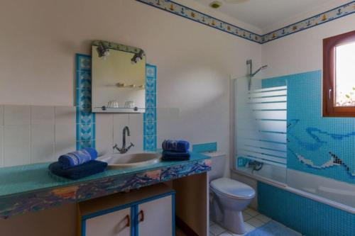 een blauwe en witte badkamer met een wastafel en een toilet bij La Bretonniere in Dragey
