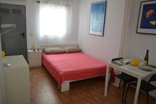una piccola camera con letto rosso e tavolo di Maspalomas Studio a Maspalomas
