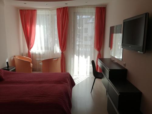 a bedroom with a bed and a television and red curtains at Apartment 33 in Hotel Iceberg in Borovets
