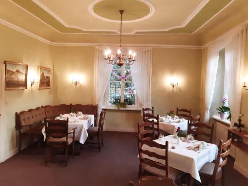 a dining room with tables and chairs and a chandelier at Pension Marienhof in Kobern-Gondorf