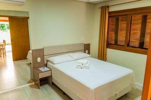 um quarto com uma cama branca e uma janela em Cantinho do Sossego em Nova Petrópolis
