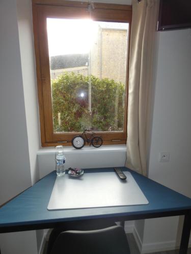 a blue table in front of a window with a bottle and scissors at Hôtel Restaurant le clos de l 'Ancien Pressoir in Commes