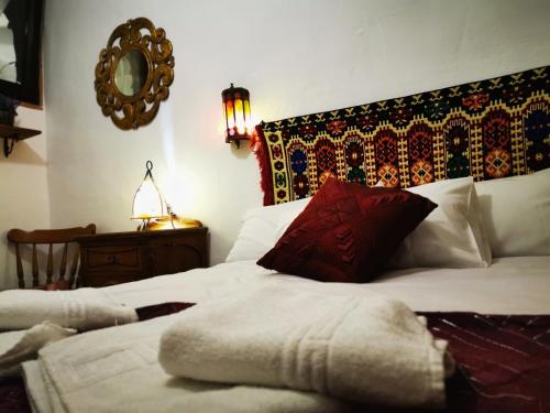 a bedroom with a bed with white sheets and red pillows at Apartamentos Alma y Montaña in Cómpeta