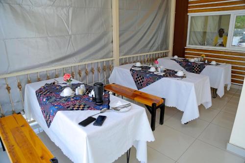 three tables in a restaurant with white table cloth at Troy Lodge in Lusaka