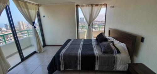 a bedroom with a bed and a view of a city at Apartamento NEO vista al mar in Iquique