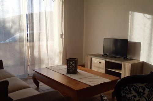 un salon avec une télévision et une table basse dans l'établissement Appartement spacieux et chaleureux à Grasse, à Grasse